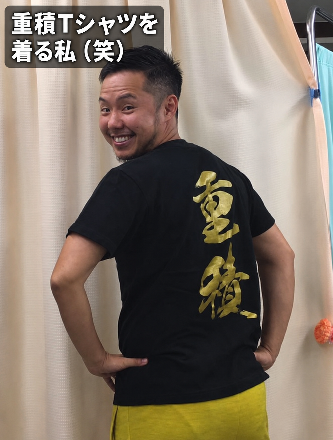 背中に金色で「重積」と書かれたTシャツを着て笑う黒沢あやと。画像内に「重積Tシャツを着る私(笑)」の文字