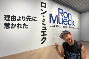 森美術館のロン・ミュエク展入口で展示案内を手にする筆者